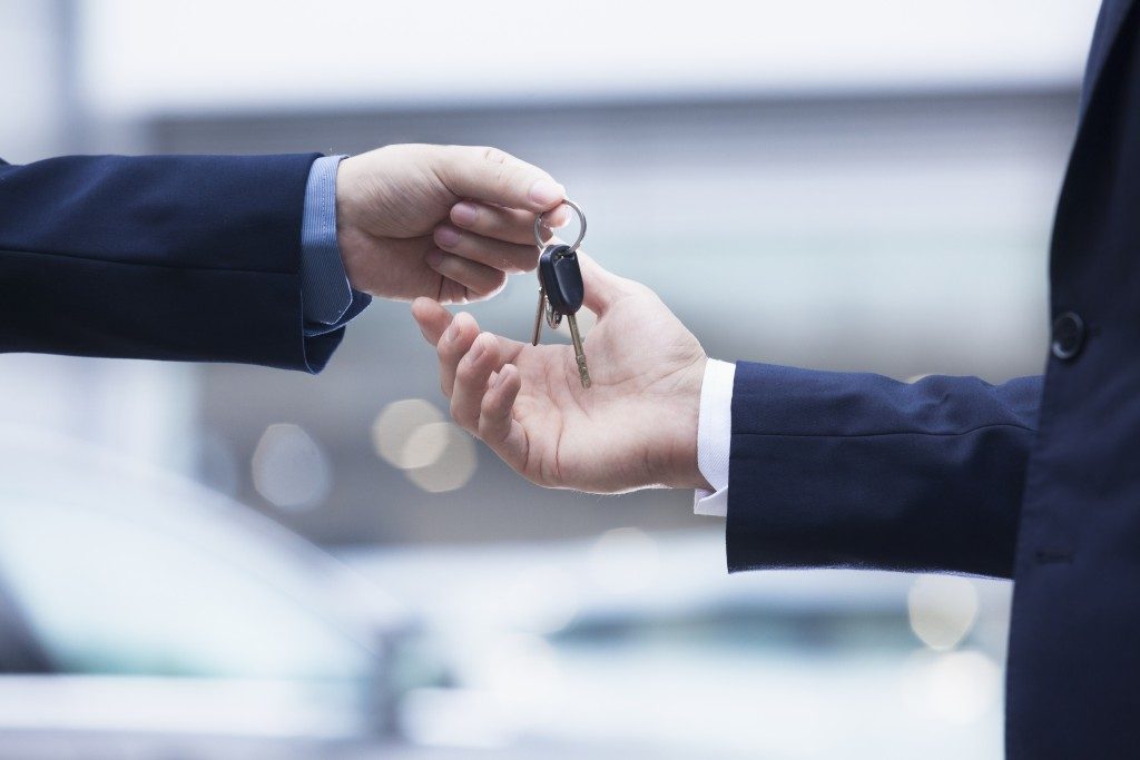 Car rental service handing over the keys for a car to a businessman