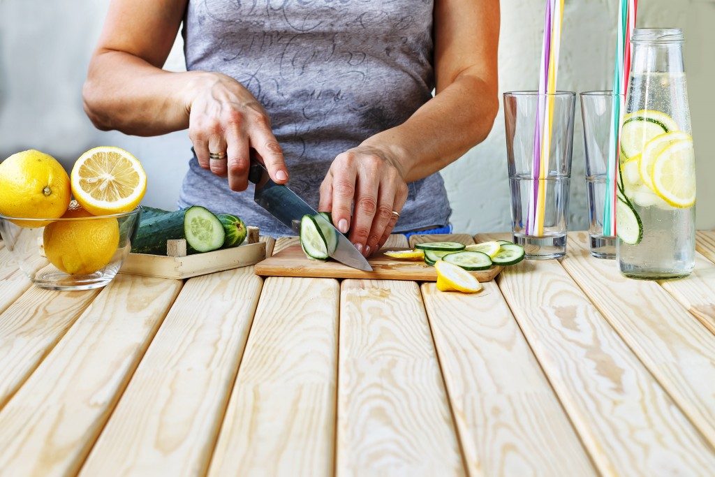 woman cutting up cucumber and lemons