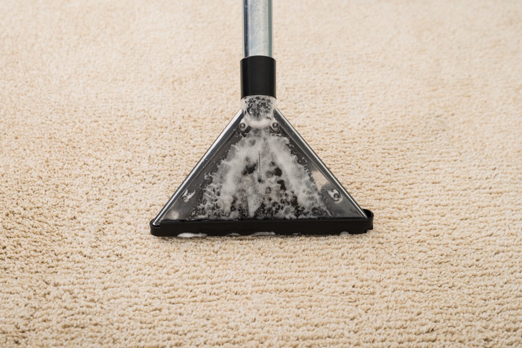 High Angle View Of Electric Vacuum Cleaner Over Carpet With Foam