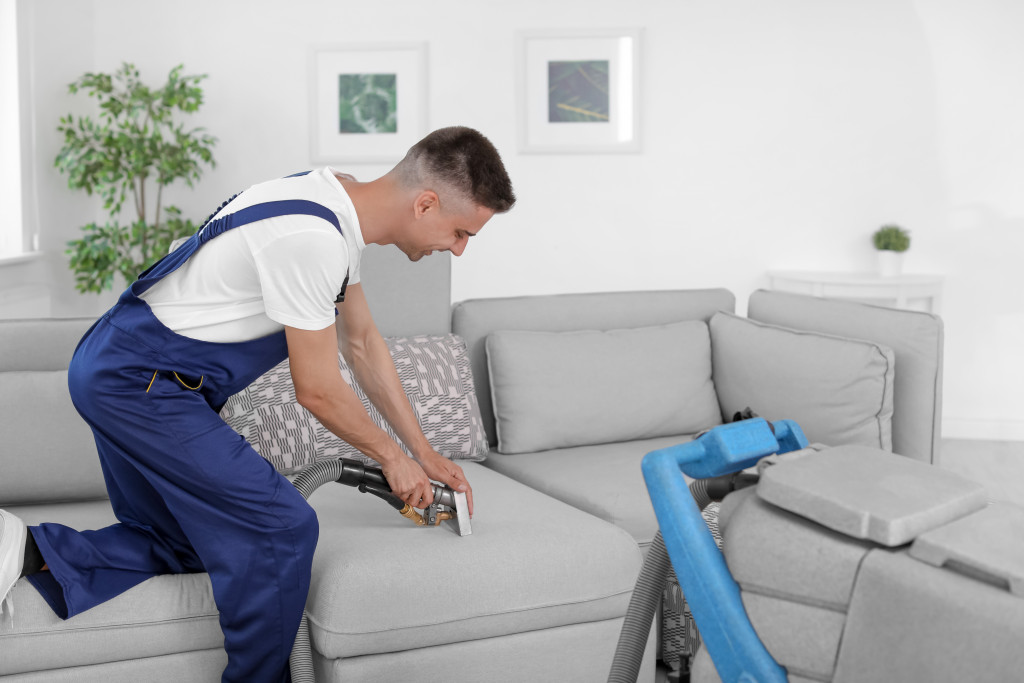 man vacuuming the couch