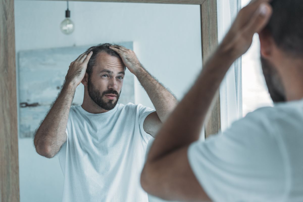 man looking at the mirror touching his hair