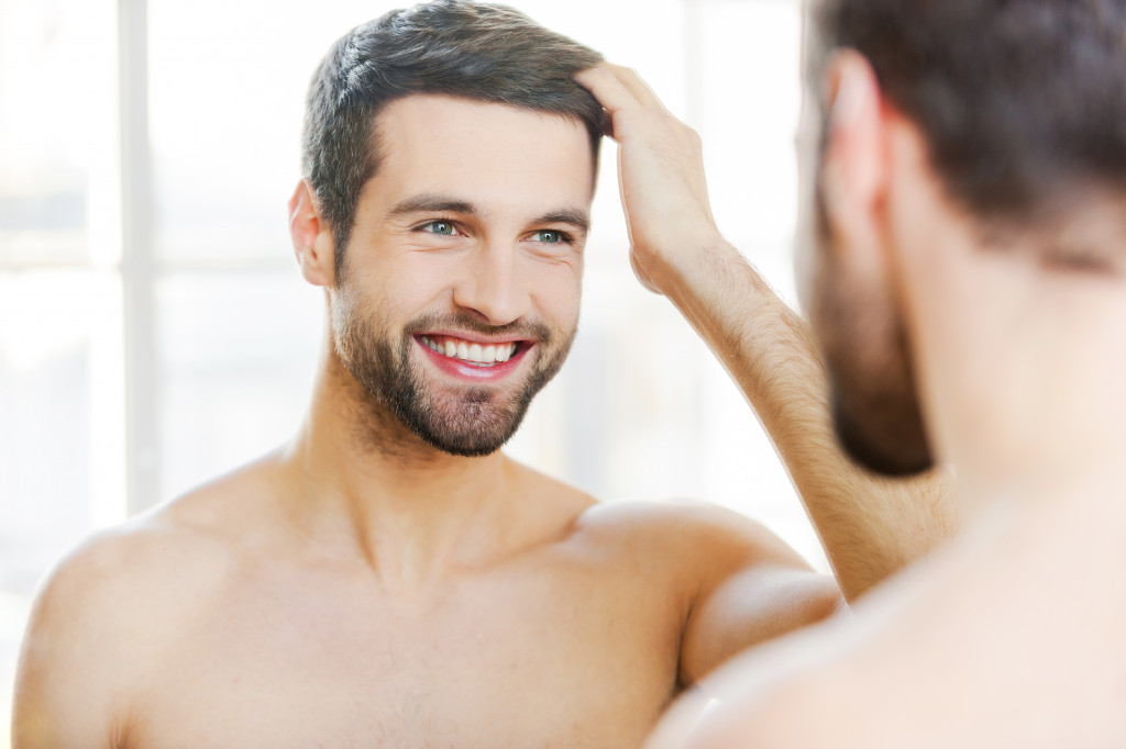 man smiling while combing through his hair