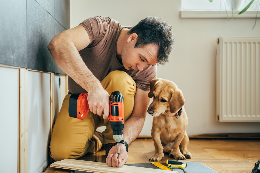 man renovating with dog besides him
