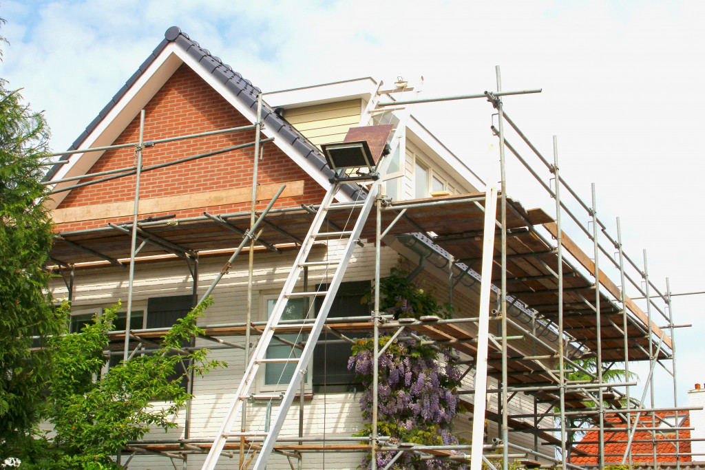 gray roofed house with scaffoldings around it being renovated