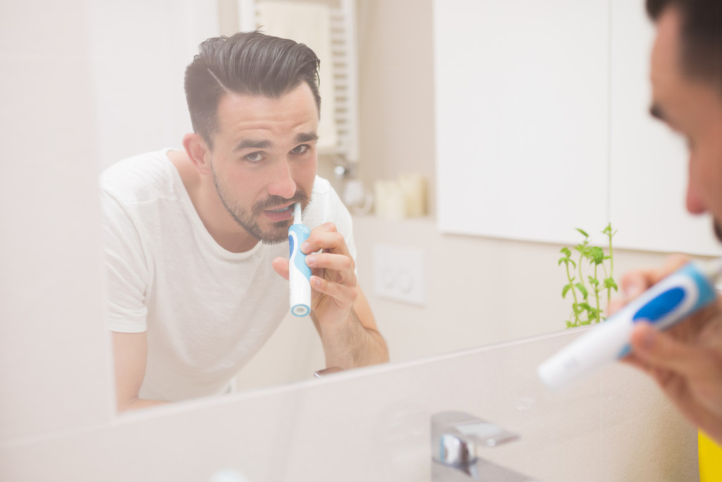 Man looking at the mirror while brushing his teeth