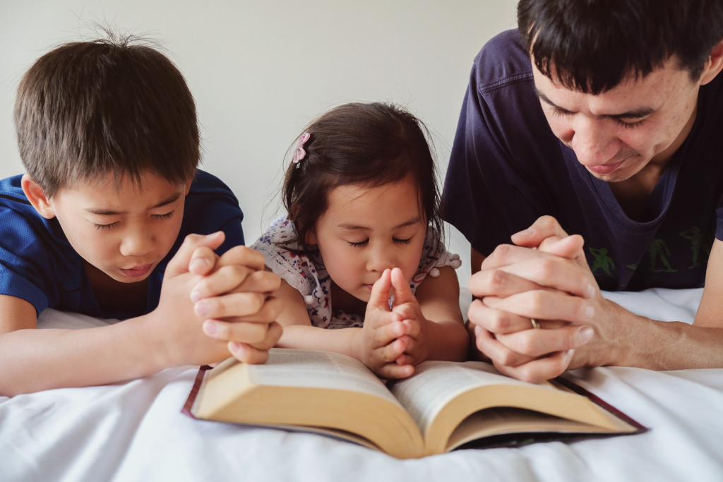 father and children praying together