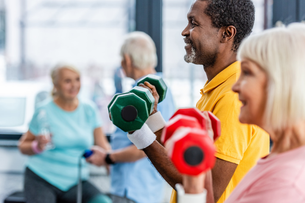 Older man exercising with other older people in a gym
