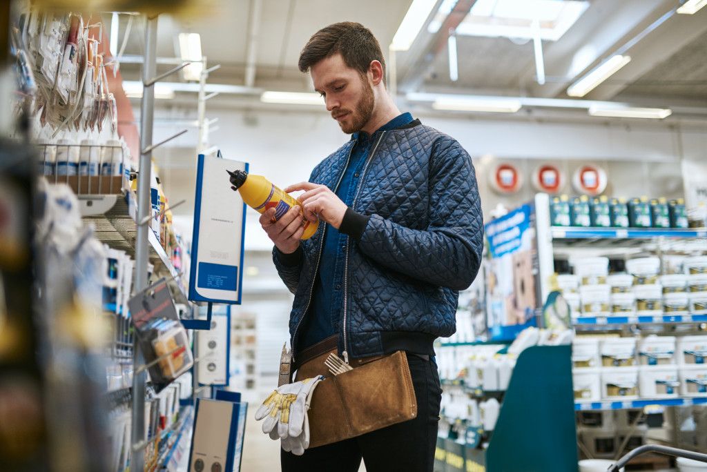 a man reading a product label in a hardwarre isle
