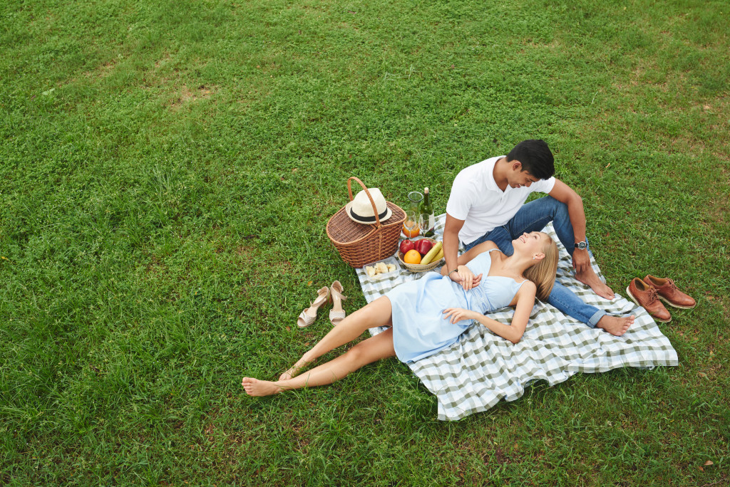 A couple relaxing while having a picnic on a grassy field