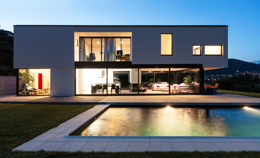 Modern home with swimming pool and lights on 