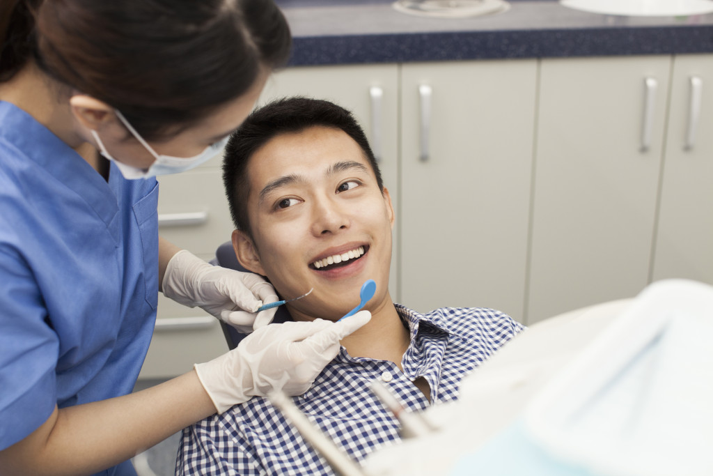 a man smiling as dentist checks teeth