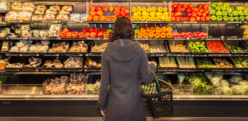 A woman in a grocery store standing in front of stocks of vegetables