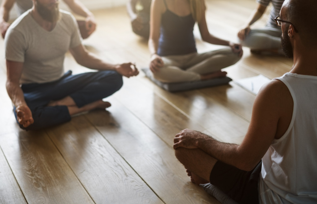Group of people sitting on wooden floor doing yoga