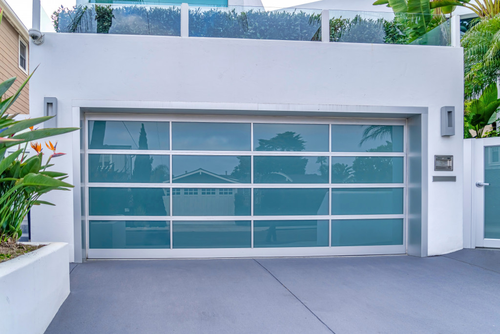 A garage with glass doors under a balcony with glass railing in a luxury house