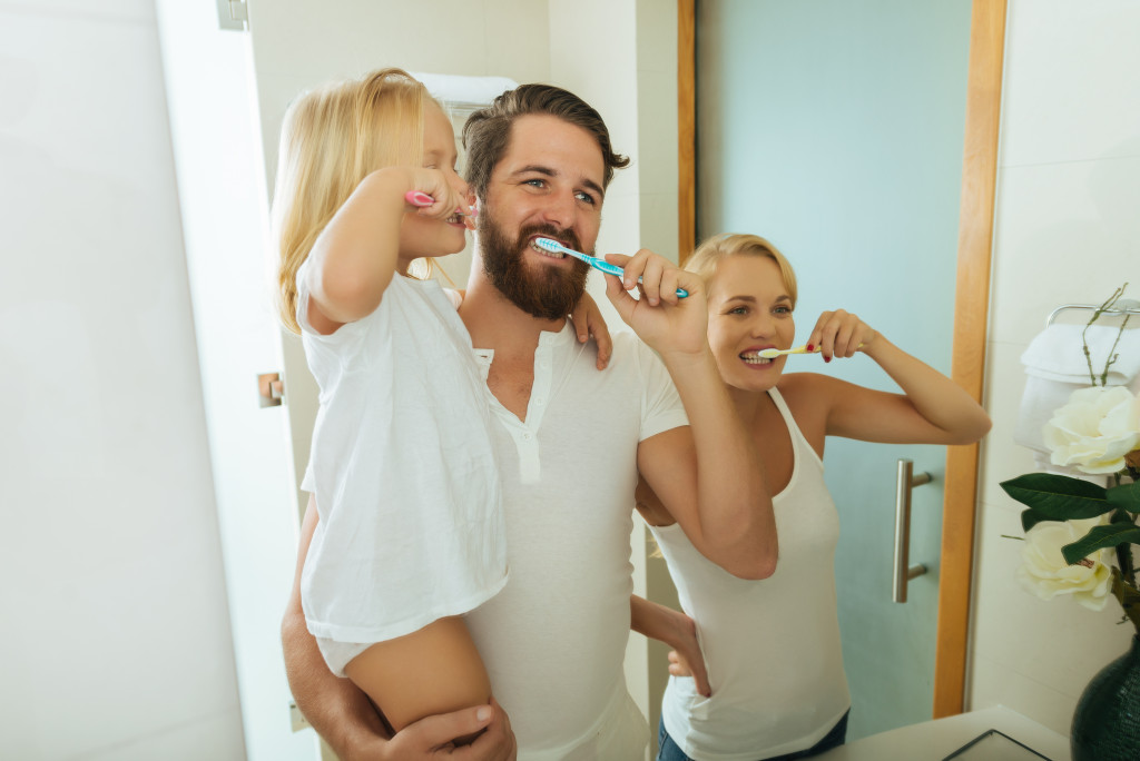 dad teaching daughter to brush her teeth