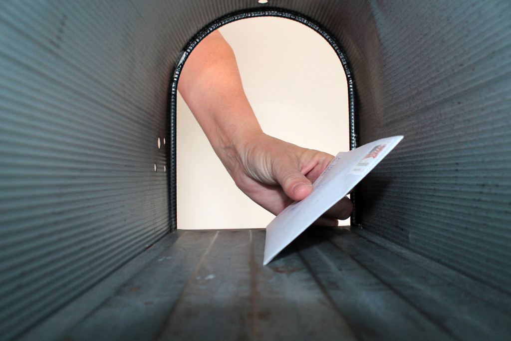 View of a hand putting letter in the mailbox from inside