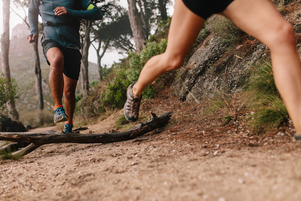 Focus on runners' legs while going through dirt path