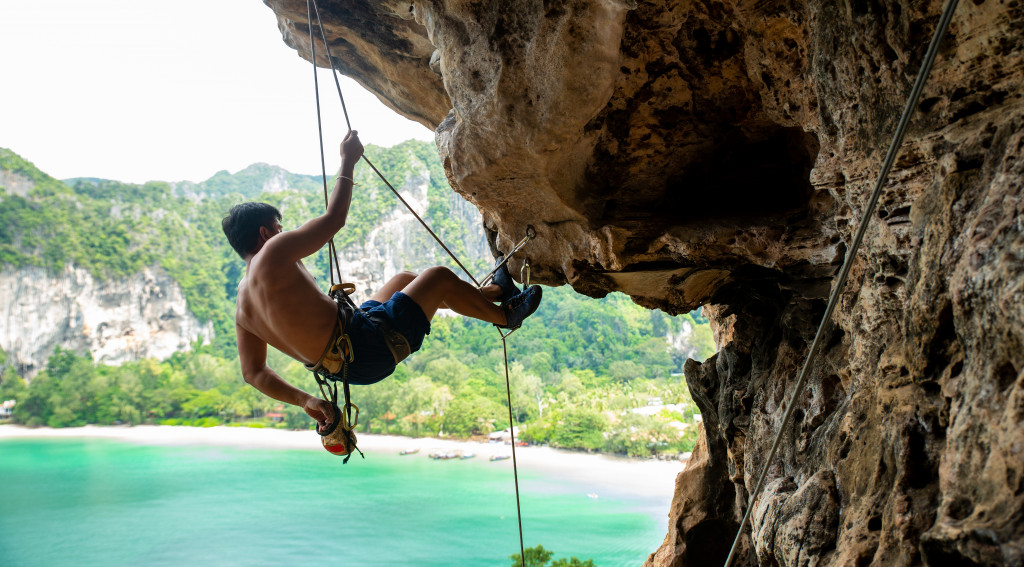 man using a safety rope to climb rocks