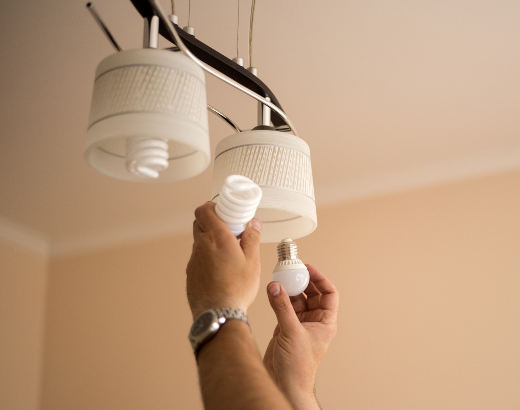 A person changing bulbs to LED in pendant home lights