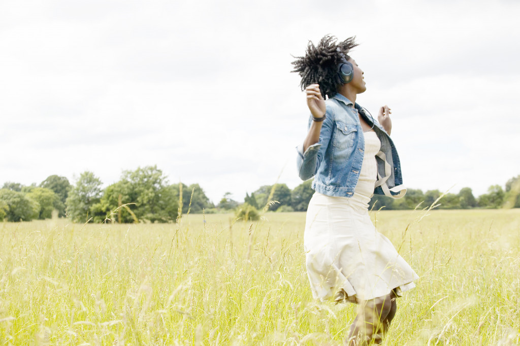 A woman listening to music and dancing in a grassy field