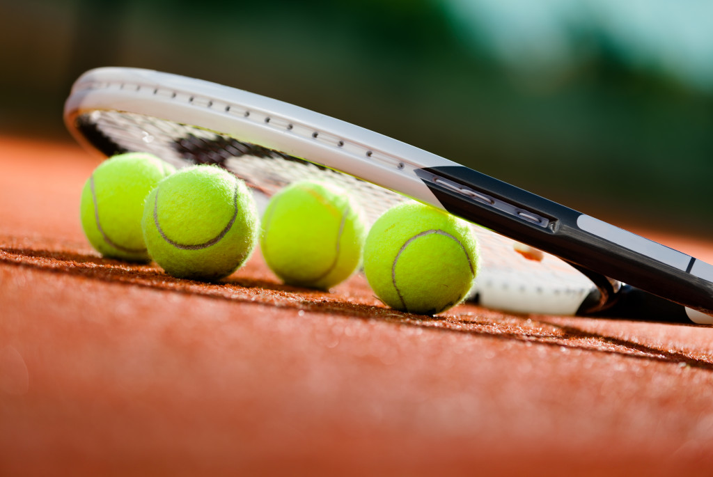 Tennis racket and balls on the court ground