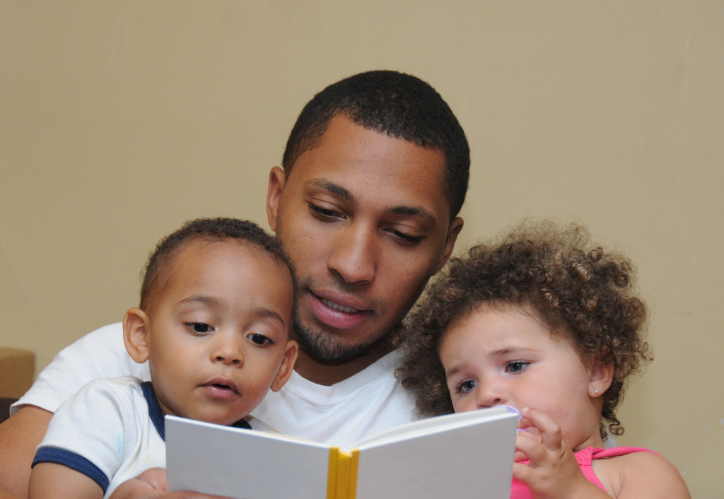 Father reading a book with his two children at home.